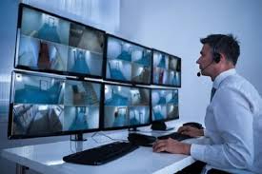 A remote security virtual assistant monitoring security cameras on multiple screens.